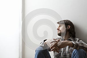 Man Siting With Hands Clasped Against Wall