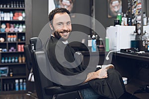 A man sits in a barber`s chair in a man`s barbershop, where he came to cut his hair.