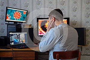 A man sits at computer monitors and is horrified by the news about the spread of the coronavirus. Covid 19