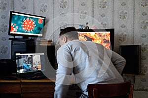 A man sits at computer monitors and is horrified by the news about the spread of the coronavirus. Covid 19