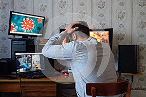 A man sits at computer monitors and is horrified by the news about the spread of the coronavirus. Covid 19