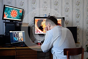 A man sits at computer monitors and is horrified by the news about the spread of the coronavirus. Covid 19