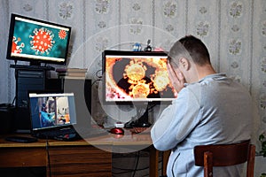 A man sits at computer monitors and is horrified by the news about the spread of the coronavirus. Covid 19