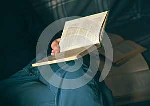 A man sits on a couch with open books and reading an encyclopedia