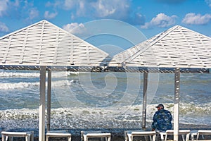 Man sits on an empty beach and looks at the big waves. It`s dangerous to swim