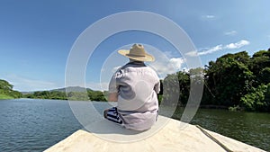 Man sits in the front of a boat as it navigates on the River
