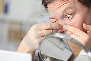 Man sits in front mirror and crushes his face