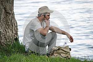 Young man is resting near a tree on the river Bank