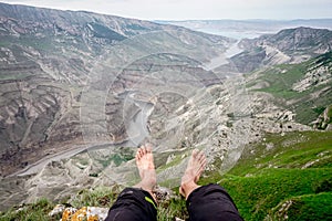 A man sits with his legs dangling over the Sulak canyon