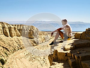 Man sits on a ledge. Canyon Ein Avdat in Negev desert