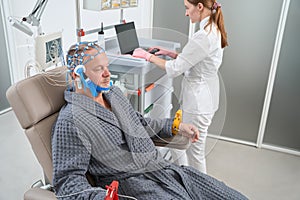 Man sits in medical chair with electrodes on his head