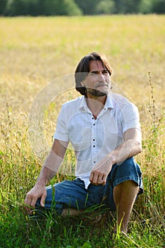 Man sits near a wheat field