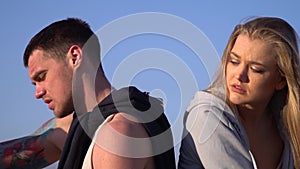 A man sits next to a woman against the blue sky after a morning quarrel