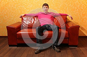 man sits on red leather sofa