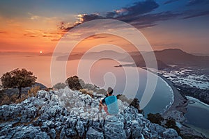 Man sits on a rock and admires the colorful sunset. The concept of individual psychology and solo travel in search of