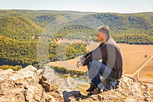 A man sits on a rock on the High Mountain and looks out into the distance on the Ural Mountains,