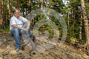 A man sits on a sandy slope and looks into the distance