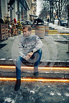 Man sits on stairs in street decorated for Christmas
