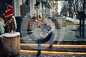 Man sits on stairs in street decorated for Christmas