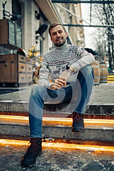 Man sits on stairs in street decorated for Christmas