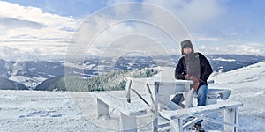 A man sits at a table in the mountains