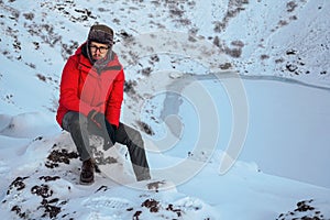 A man sits on top of the crater lake Kerid. Winter travel in Iceland. Portre men in a red jacket against the backdrop of a volcano