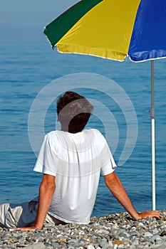 Man sits under umbrella