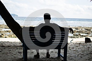 Man Sitting alone on a bench near Seashore