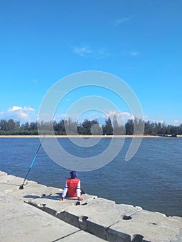 Man sitting alone on pier fishing