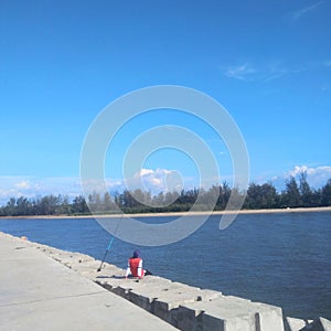 Man sitting alone on pier fishing activity on a sunny day -image