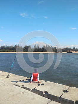 Man sitting alone on pier fishing activity on a sunny day -image