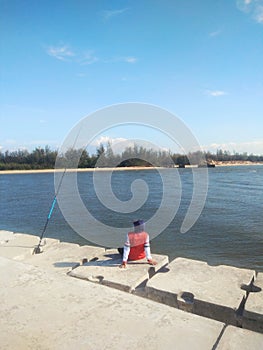 Man sitting alone on pier fishing activity on a sunny day -image