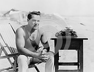 Man sitting at the beach with his typewriter