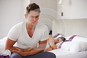 Man Sitting On Bed And Feeling Unwell photo