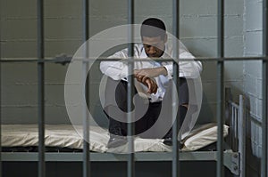 Man Sitting On Bed In Prison Cell