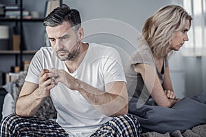 Man sitting in bed and taking off his wedding ring after argument with his wife