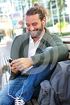 Man sitting on bench listening to music with earphones