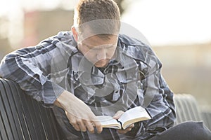 Man sitting on bench and reading bible and thinking