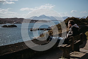 Man sitting on a bench, relaxing in the sun in Kyle of Lochalsh, Scotland. photo