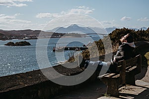 Man sitting on a bench, relaxing in the sun in Kyle of Lochalsh, Scotland. photo