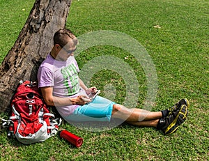 Man sitting beneath the tree and using his tablet