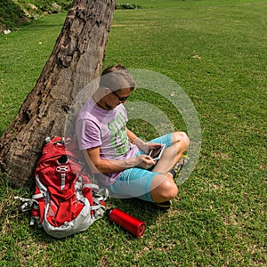 Man sitting beneath the tree and using his tablet