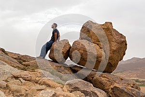 Man sitting on big rocks on the edge of a mountain