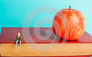 Man is sitting on a book. the concept of education. apple and books, blue background, place for text, back to school, copy space