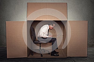 Man sitting in a box working on laptop computer