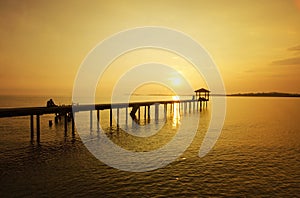 A man sitting on the bridge alone during sunset