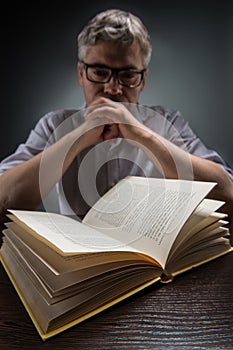 Man sitting at brown table and reading book.