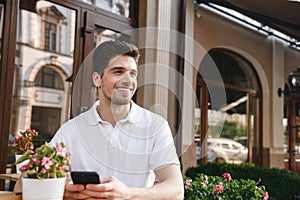 Man sitting in cafe outdoors while using mobile phone.