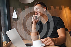 Man sitting in cafe with phone, laptop and coffee