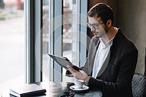 a man sitting in a cafe with tablet. Casual Man Using Tablet Computer Sitting in Cafe Surfing Internet